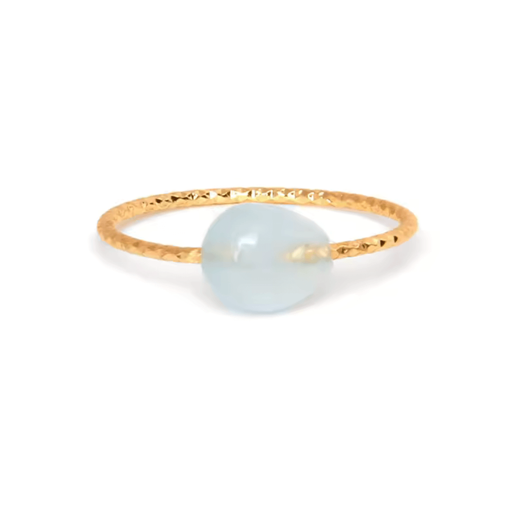 Gold ring with a translucent blue gemstone, minimalist crystal ring design.